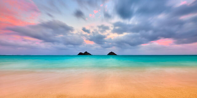 A sea shore under a cloudy purple sky.